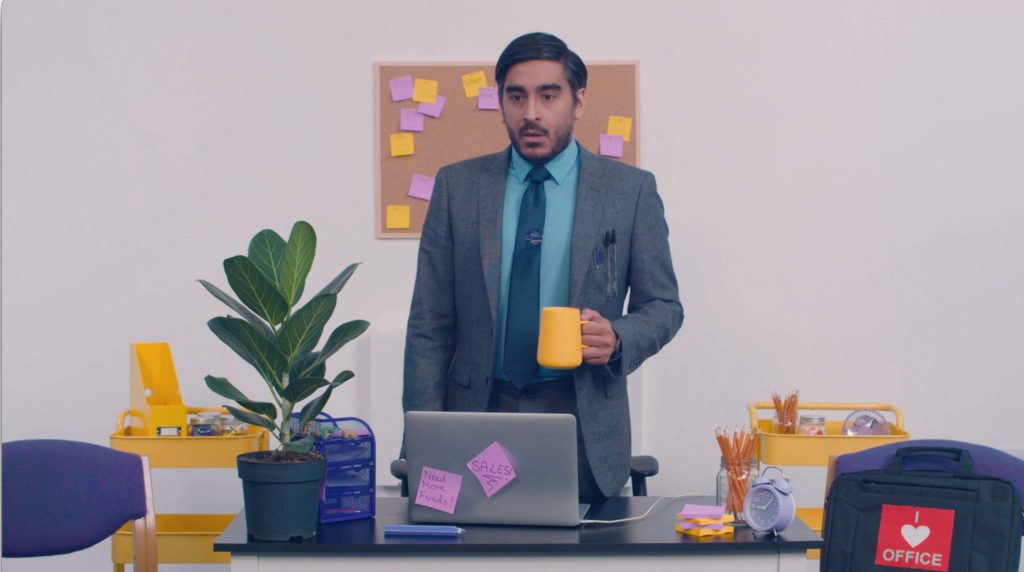 A man standing by a desk holding a mug